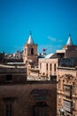 Vertical shot of St. Augustine Church with other building rooftops. Valletta, Malta.