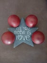 Vertical shot of a star with a quote  all you need is love and four red balls on the floor Royalty Free Stock Photo