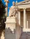 Vertical shot of a statue by the entrance of Academy of Athens university in Athens, Greece