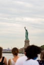 Vertical shot of the Statue of Liberty in front of the crowd in New York City, United States