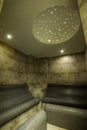 Vertical shot of a steam room design with a bench and marble wall tiles