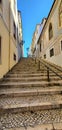 Vertical shot of stone stairs between buildings under the blue sky Royalty Free Stock Photo