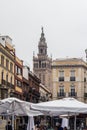 Vertical shot of a street in the city of Seville and the bell tower of the Giralda behind buildings