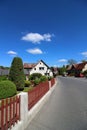 Vertical shot of a street of houses with green shrubs inside the red fence in a clear blue sky Royalty Free Stock Photo