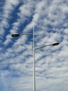 Vertical shot of street lamps on a lamppost under a blue cloudy sky Royalty Free Stock Photo