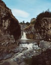 Vertical shot of a strong waterfall flowing in the river between enormous rocks