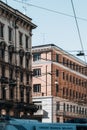 Vertical shot of stylish beige buildings and a top of a white tram in Milano streets of Italy