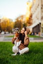 Vertical shot of a stylish dog-owner female hugging her little yorkshire terrier, wearing a fashionable hoodie, sitting on the Royalty Free Stock Photo