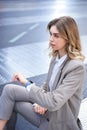 Vertical shot of successful corporate woman in suit, checking time on watch, looking away, waiting for someone in city Royalty Free Stock Photo
