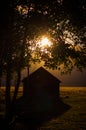 Vertical shot of the sun rising over a cute country house in the middle of a forest Royalty Free Stock Photo