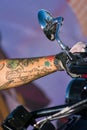 Vertical shot of a tattooed hand of a biker holding the motorcycle