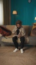 Vertical shot of a teenager, young man sitting on a sofa, couch, reading a document, paper, admission, waiting to see Royalty Free Stock Photo