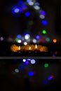 Vertical shot of three candles burning in abstract background with bokeh lights Royalty Free Stock Photo