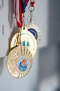 Vertical shot of three hanging gold-colored medals from school events