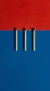 Vertical shot of three matches on a blue and red geometric surface Royalty Free Stock Photo