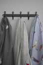 Vertical shot of three shirts with feather patterns hanging from a black hanger