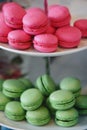 Vertical shot of a tiered tray with pink and green macarons