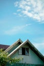 Vertical shot of the top of an old house with broken glass window against blue sky Royalty Free Stock Photo