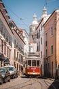 Vertical shot of a tram with CocaCola advertisement on it in the sunny cobbled streets of Lisbon