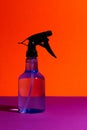 Vertical shot of a transparent sprayer bottle on a bold vibrant orange background