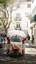 Vertical shot of a Tuc Tuc vehicle riding down the crowded streets of Lisbon