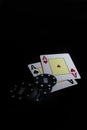 Vertical shot of two ace cards and poker chips under the lights on a black background Royalty Free Stock Photo