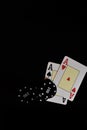 Vertical shot of two ace cards and poker chips under the lights on a black background Royalty Free Stock Photo