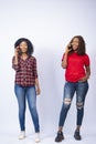 Vertical shot of two black females smiling and making phone calls Royalty Free Stock Photo