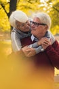 Vertical shot of two elderly grey-haired caucasian people embracing each other and spending time outside, enjoying Royalty Free Stock Photo