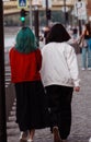 Vertical shot of two girls from the back walking on the street, one of them has blueish hair