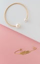 Vertical shot of two golden bracelets and silver ring on slanted pink and white background Royalty Free Stock Photo