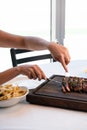 Vertical shot of two hands cutting delicious bone in ribeye steak platter Royalty Free Stock Photo