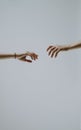 Vertical shot of two hands reaching for one another on a gray background.Distant love concept