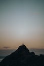 Vertical shot of two person standing on the top of a mountain on the clear sky background at sunset Royalty Free Stock Photo