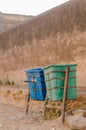 Vertical shot of two plastic trash bins on stilts, against an old plaster-peeled wall Royalty Free Stock Photo