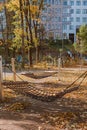 Vertical shot of two rope hammocks attached to wooden posts over the beautiful yellow fall leaves