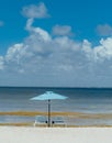 Vertical shot of the two sun loungers under the beach umbrella against the sea Royalty Free Stock Photo