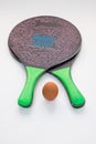 Vertical shot of two wooden rackets and an egg.