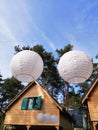 Vertical shot of unique simple white chandeliers in front of log cabins