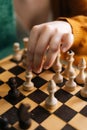 Vertical shot of unrecognizable woman making chess move with piece sitting at table in dark room, selective focus. Royalty Free Stock Photo