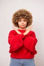 Vertical shot of upset young woman with curly hair keeps arms crossed with sad expression shows stop gesture, wears red Royalty Free Stock Photo