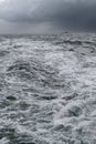 Vertical shot of very rough sea with black dramatic clouds in the sky and small ship on the horizon. Storm at the sea Royalty Free Stock Photo