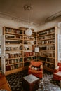 Vertical shot of a vintage room with bookshelves and orange armchairs