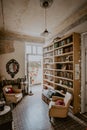 Vertical shot of a vintage room`s interior with a bookshelf and white armchairs