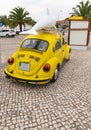 Vertical shot of a vintage yellow Volkswagen beetle car with a dolphin figure on a cobblestone road Royalty Free Stock Photo