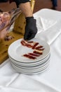 Vertical shot of a waiter cutting the slices of tasty Jamon