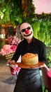 Vertical shot of the waiter serving the food with wearing clown mask in Wood Cafe In Ajman, Emirates