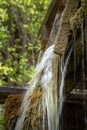 Vertical shot of a water inlet to an old mill wheel on the background of green leaves Royalty Free Stock Photo