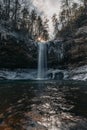 Vertical shot of a waterfall cascading down between large frozen rocks Royalty Free Stock Photo