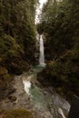 Vertical shot of a waterfall cascading down the rocks in a forest surrounded by wild nature